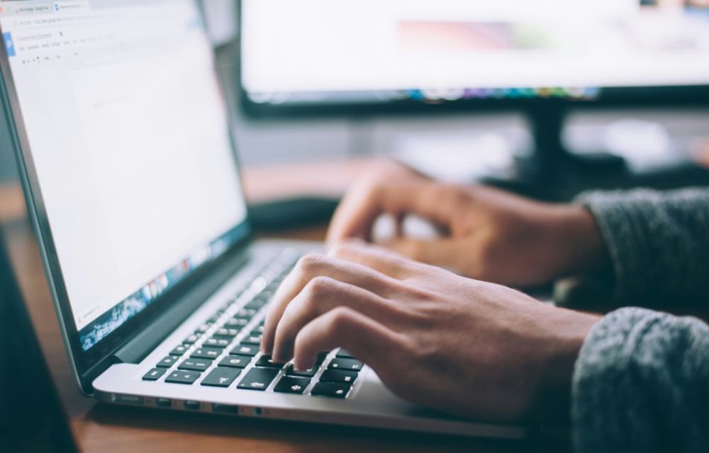 Hands typing on a laptop keyboard